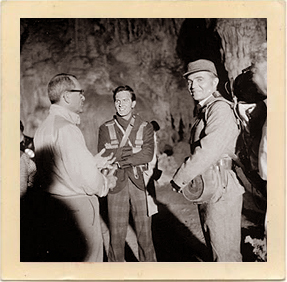 Pat Boone (center) and James Mason (right) discuss a scene with the director on location in the depths of Carlsbad Caverns.